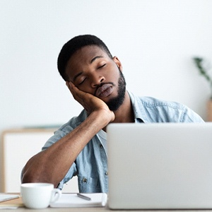 tired person falling asleep at laptop