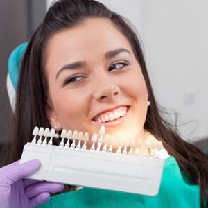 A woman selecting tooth color for a cosmetic dental treatment