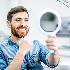 Male patient examining dental implants in Fayetteville, NC in mirror