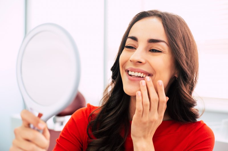 A woman looking at her new cosmetic dentistry treatments in a mirror
